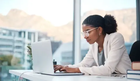 Young professional working on laptop in office.